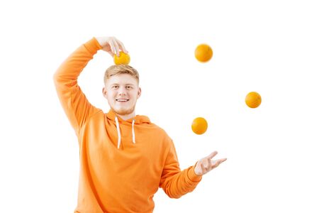 young man in orange hoody with oranges on white backgroundの写真素材