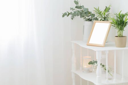 wooden frame on vintage white shelf with flowers and plantsの写真素材