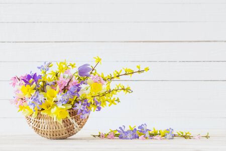 spring flowers in basket on white wooden backgroundの写真素材