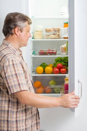 mature men at fridge  with foodの写真素材