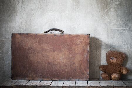 brouwn teddy bear and old suitcase on  grunge backgroundの写真素材