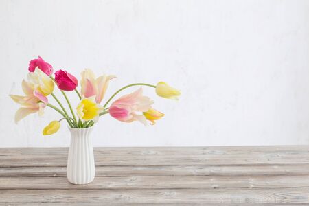 yellow and pink tulips in vase on background old white wallの写真素材
