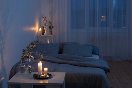 night interior of bedroom with flowers and burning candlesの写真素材