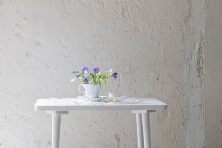 viola flowers in white cup on white backgroundの写真素材