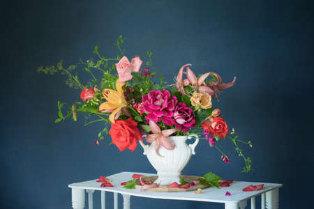 bouquet of summer flowers in vase on vintage white wooden shelf on dark backgroundの写真素材