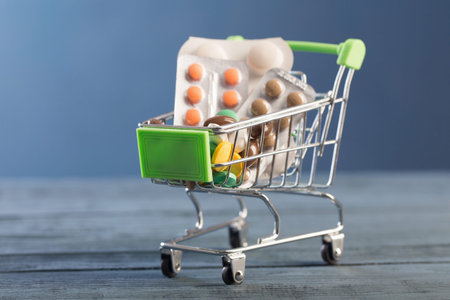 medicines and pills in small toy trolley on blue background
