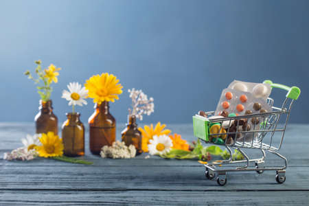 pills and wild plants on blue background, natural medicine conceptの写真素材