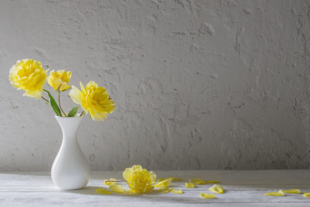 yellow roses in white vase on background white wall