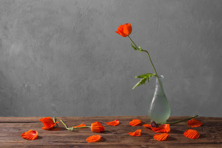 red poppies in vase on wooden table