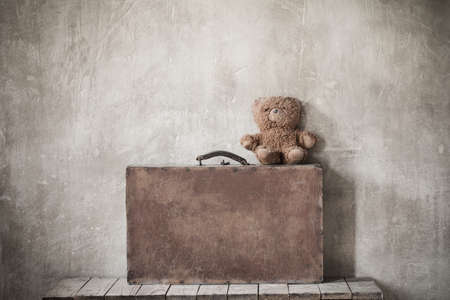 brouwn teddy bear and old suitcase on grunge backgroundの写真素材