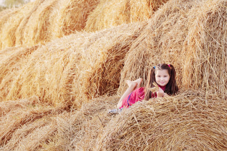 happy little girl in red dress on stack sraw