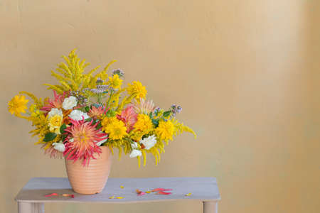 yellow and red flowers in vase on vintage shelfの写真素材