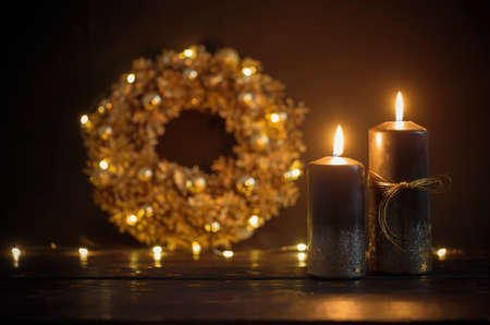Christmas golden wreath with black burning candles on dark wooden backgroundの写真素材