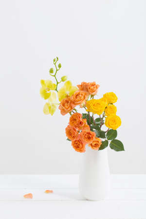 roses and orchids in vase on white backgroundの写真素材