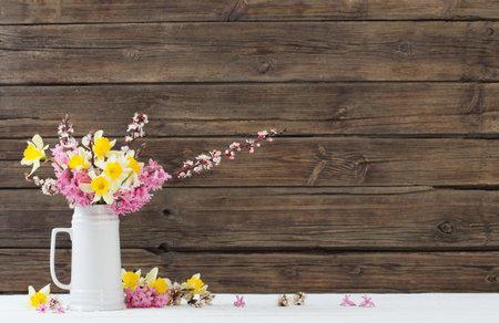 spring flowers in white jug on wooden background