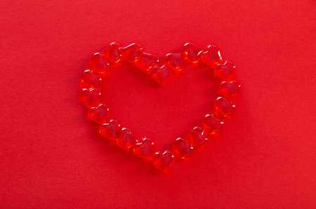 red glass hearts on red backgroundの写真素材