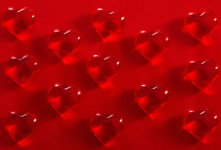 red glass hearts on red backgroundの写真素材