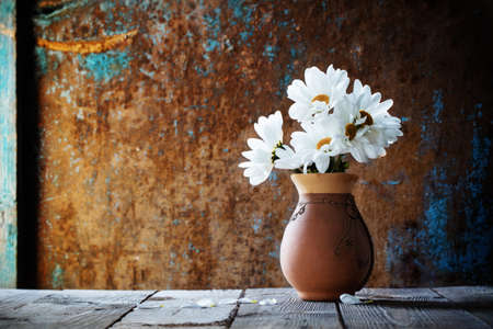 white flowers in jug on old wooden painted backgroundの写真素材