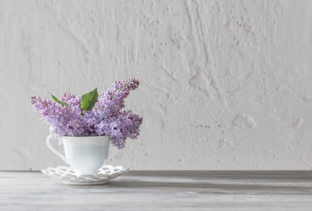 bouquet of lilacs in ceramic cup on old wooden table