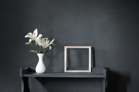flowers in vase and wooden frame on background dark wall