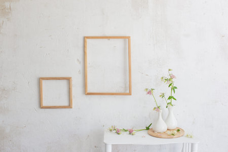 flowers in vase and wooden frames on white interior