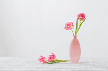 tulips in pink vase on white tableの写真素材