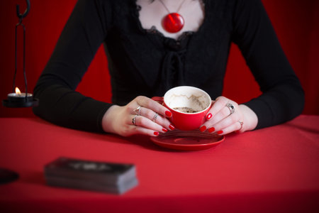 young girl in a black dress is engaged in fortune telling on coffee grounds on red background