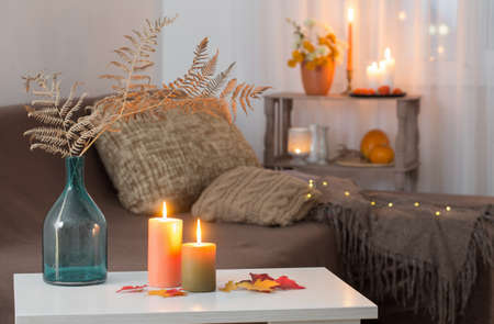 burning candles with autumn decor on white table at homeの写真素材