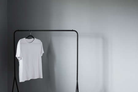 white t-shirt on black hanger against gray wallの写真素材