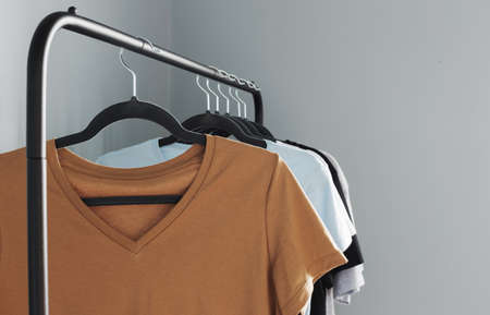 T-shirts of neutral colors on black hanger against gray wallの写真素材