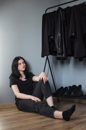 teen girl in black jeans and a t-shirt near hanger with black clothesの写真素材