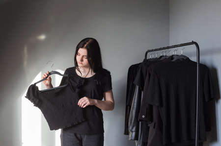 teen girl in black jeans and a t-shirt near hanger with black clothesの写真素材