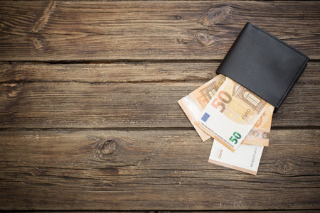 euro in black wallet on dark wooden background