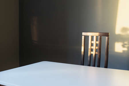 white table and wooden chair on background gray wall in sunlightの写真素材