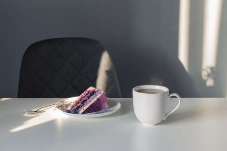 blueberry lavender cheesecake on plate and cup of tea on white tableの写真素材