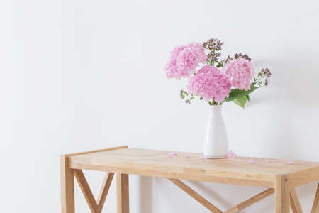 pink hydrangea in white vase on wooden shelf on background white wallの写真素材