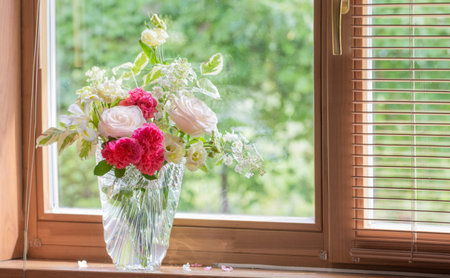 summer bouquet in glass vase on windowsill in wooden house