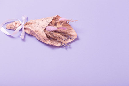bouquet of dried flowers in craft paper on lilac backgroundの写真素材