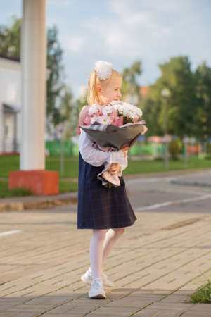 little schoolgirl with bouquet go to school in sunny dayの写真素材