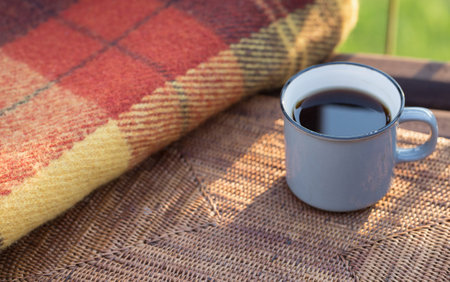 cup of tea and warm plaid on wooden bench outdoorの写真素材