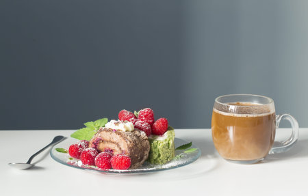 cup of coffee and dessert with raspberries on white table on background blue wall