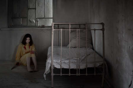 scary crazy girl covered in blood with knife in locked room at nightの写真素材