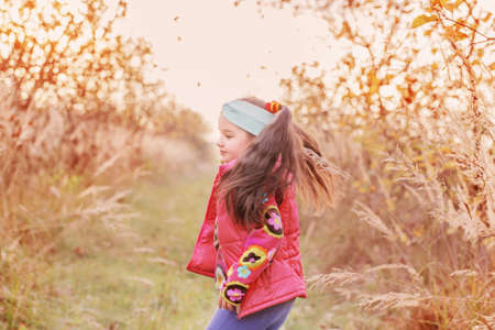 happy schoolgirl in autumn apple orchardの写真素材
