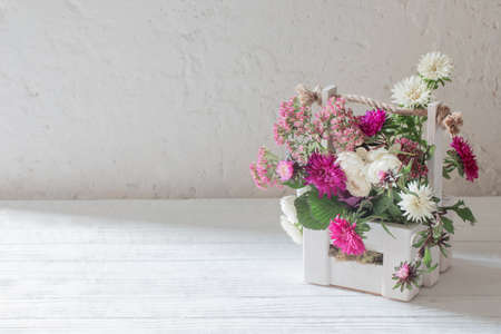 pink and white flowers in wooden basket on white backgroundの写真素材