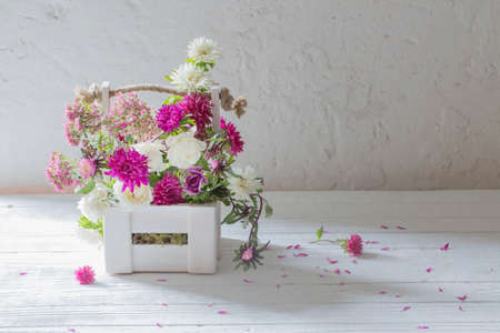 pink and white flowers in wooden basket on white backgroundの写真素材