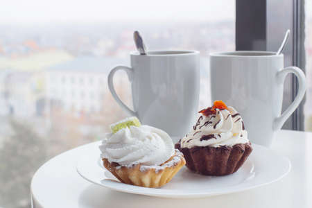 ywo cupcakes and two cups on table in cafeの写真素材