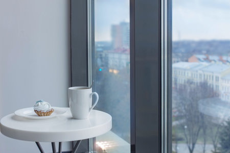 cupcake with cup on white table near window in cafe