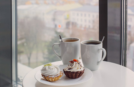 ywo cupcakes and two cups on table in cafeの写真素材