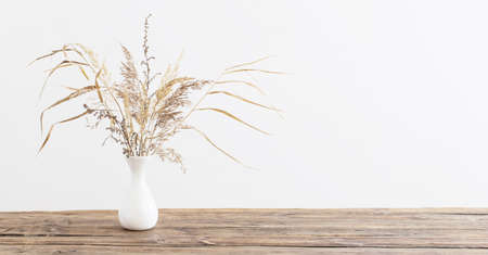 dried flowers in vase on wooden table on white backgroundの写真素材