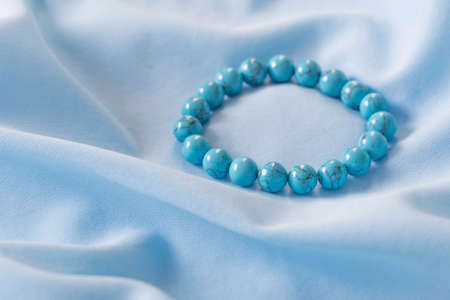 turquoise bracelet made of natural stones on blue silk fabricの写真素材
